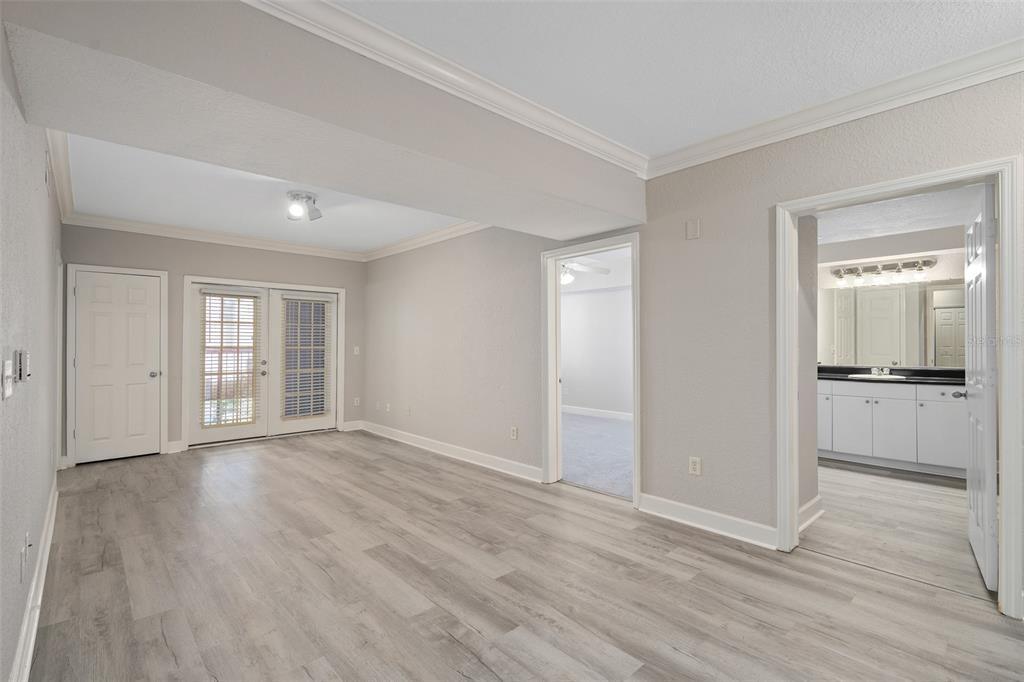 A room with light wood-look flooring, a ceiling beam, French doors, and two doorways — 206 E SOUTH STREET UNIT 6007, ORLANDO, FL