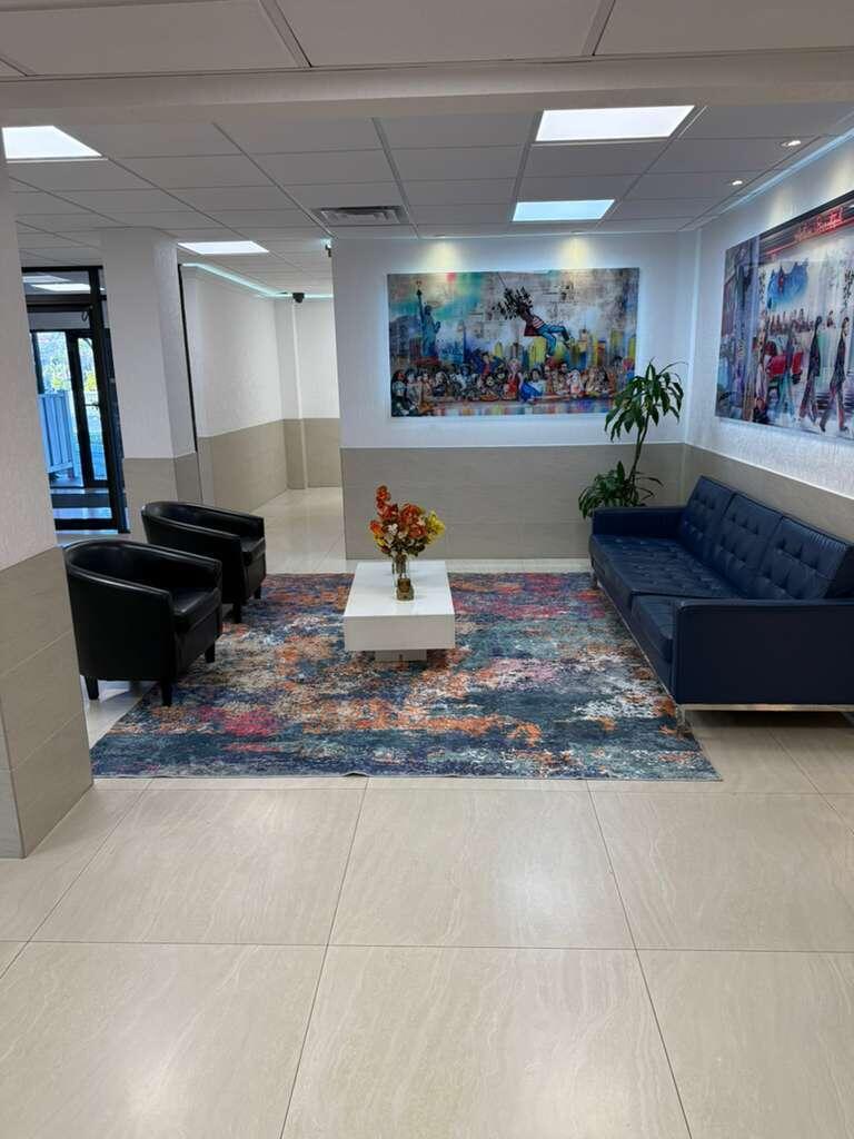 A waiting area features a blue sofa, two black chairs, a coffee table, and colorful artwork — 4164 Inverrary Drive # 302, Lauderhill FL 33319, LAUDERHILL, FL