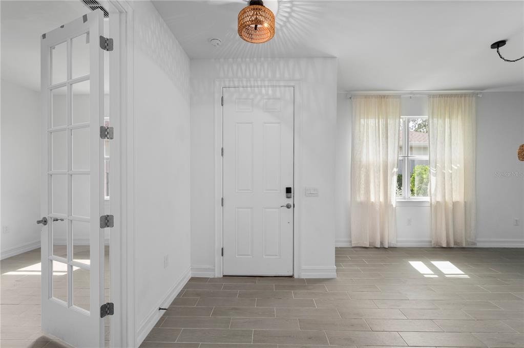 A bright entryway features white walls, gray tile flooring, a front door, and French doors — 43620 SPARROW DRIVE, PUNTA GORDA, FL