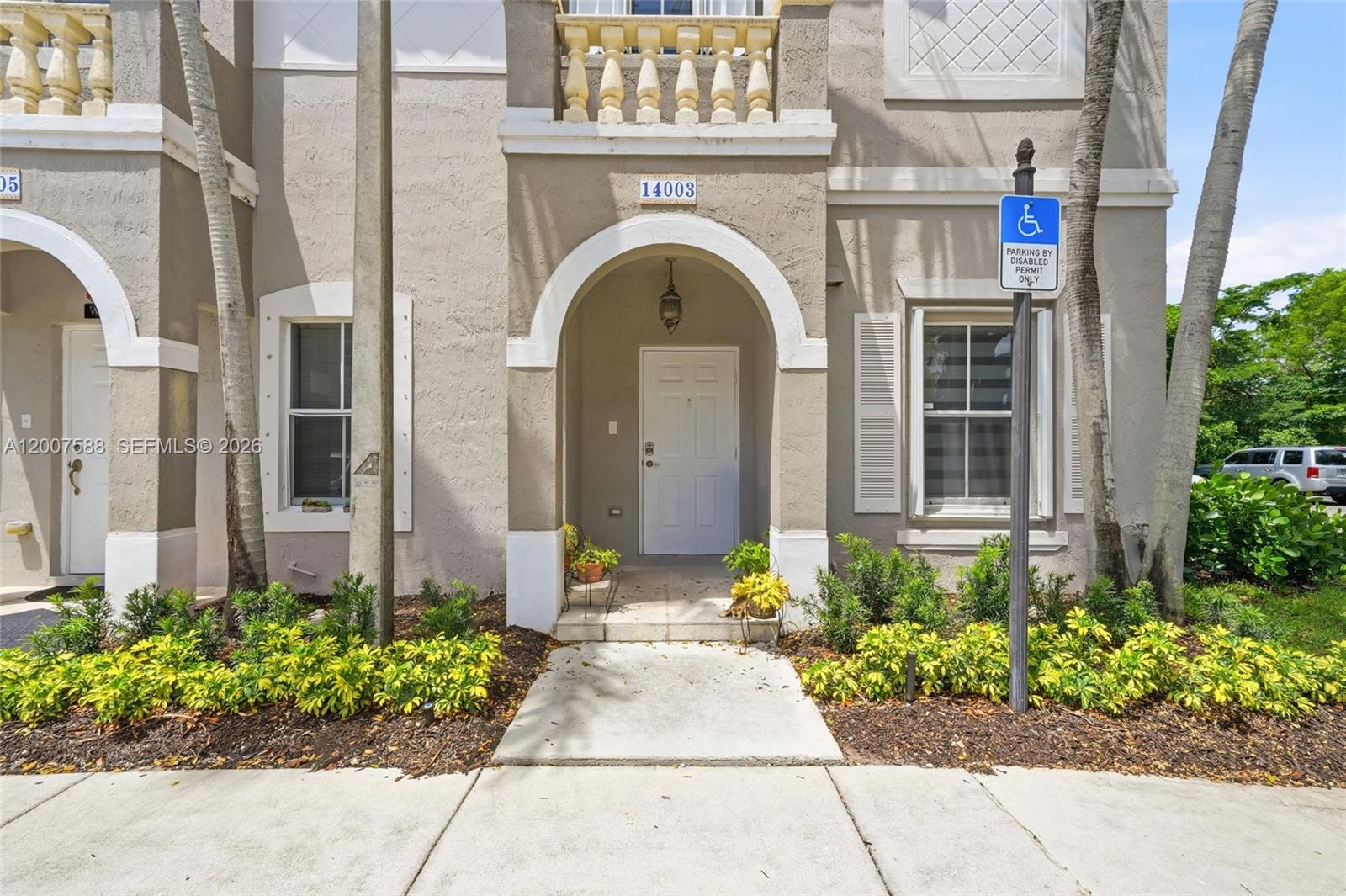 The exterior view shows a beige townhouse entrance with an arched doorway and a handicap sign — MIRAMAR, FL