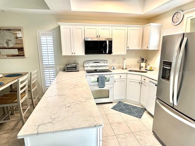 A kitchen features white cabinetry, a marble-patterned countertop, stainless steel appliances, and tile flooring — 8369 WINGATE DRIVE UNIT 2114, SARASOTA, FL