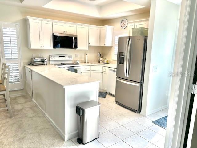 A kitchen features white cabinetry, stainless steel appliances, and a quartz-topped island — 8369 WINGATE DRIVE UNIT 2114, SARASOTA, FL