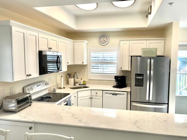 A kitchen features white cabinetry, stainless steel appliances, and a light-colored quartz countertop — 8369 WINGATE DRIVE UNIT 2114, SARASOTA, FL