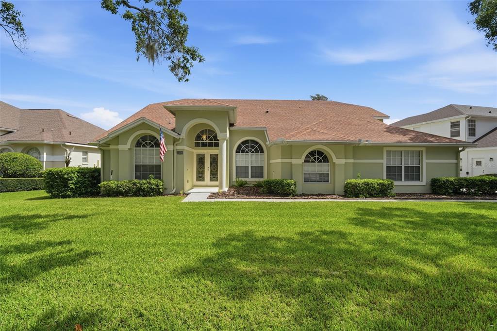 A single-story house with a light green exterior, arched windows, and a brown shingled roof — 1526 CHERRY LAKE WAY, LAKE MARY, FL