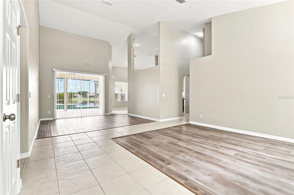 An open-concept living area features light-colored tile flooring, wood-look laminate, and sliding glass doors — 1526 CHERRY LAKE WAY, LAKE MARY, FL