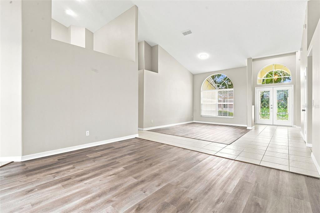 A living room with light gray walls, wood-look flooring, tile entryway, and vaulted ceilings — 1526 CHERRY LAKE WAY, LAKE MARY, FL