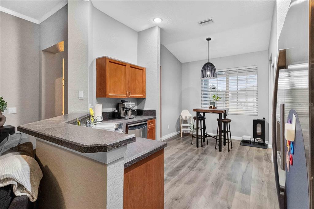 A kitchen with wood cabinets, dark countertops, and a dining area with a high table — 11326 LAUREL BROOK COURT, RIVERVIEW, FL