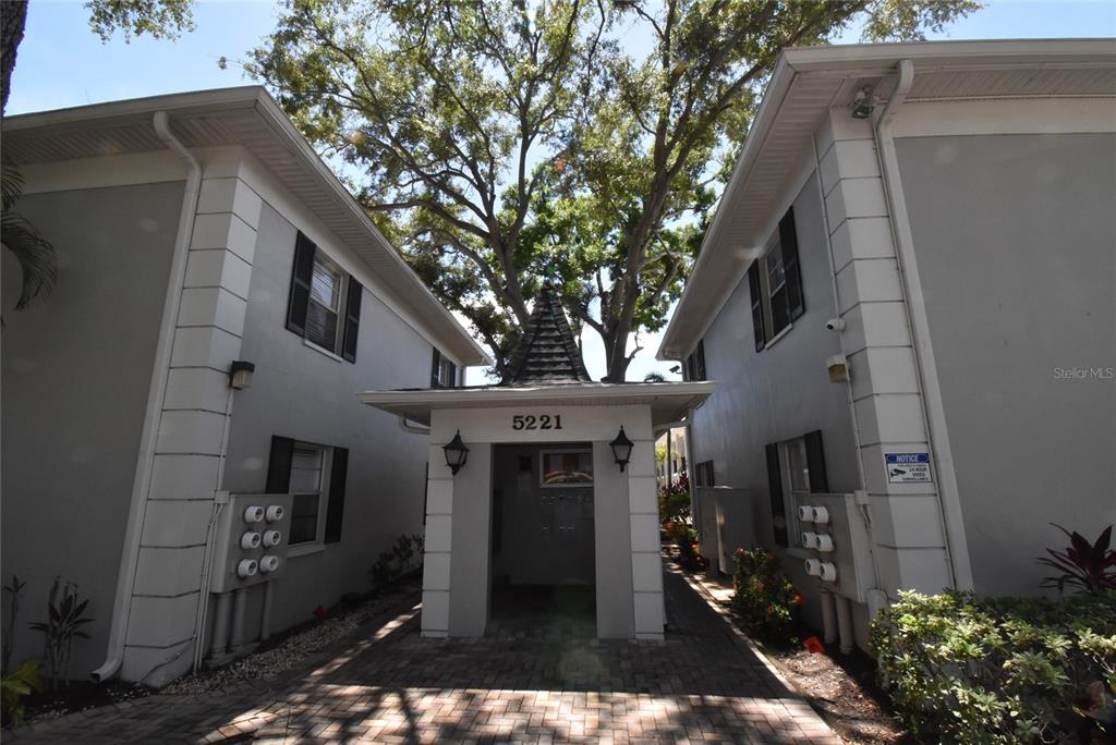 A paved walkway leads to the entrance of a two-story apartment building with gray siding — 5221 BAYSHORE BOULEVARD UNIT 45, TAMPA, FL