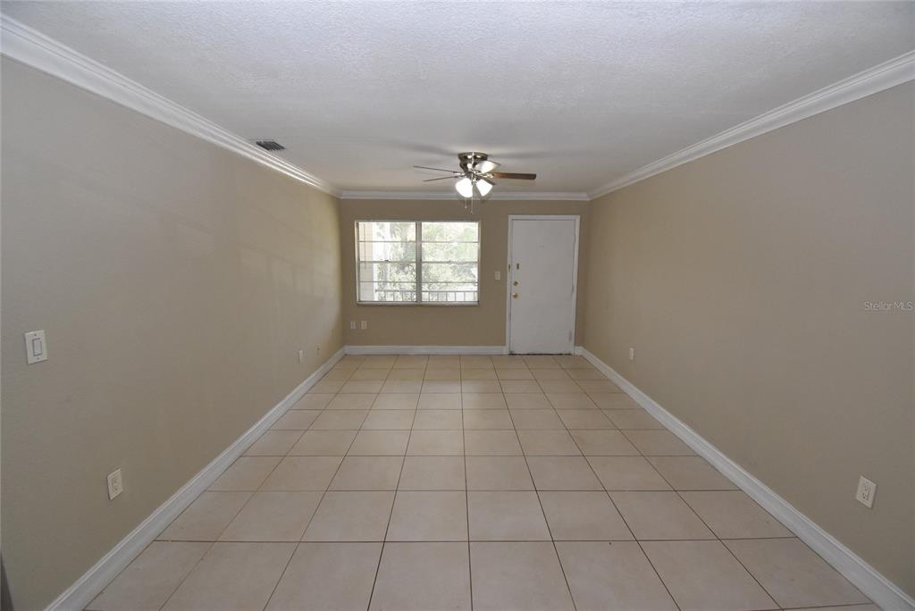 An empty room with beige walls, tile flooring, a ceiling fan, and a white door — 5221 BAYSHORE BOULEVARD UNIT 45, TAMPA, FL