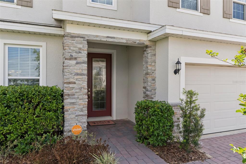The exterior of a home features a stone-accented entryway, a red front door, and a garage — 14321 CRESTAVISTA AVENUE, CLERMONT, FL