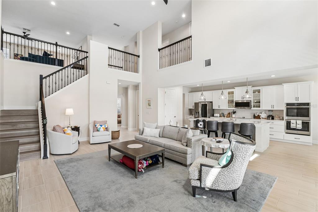 A spacious open-concept living room features a high ceiling, a staircase, and a modern kitchen — 14321 CRESTAVISTA AVENUE, CLERMONT, FL