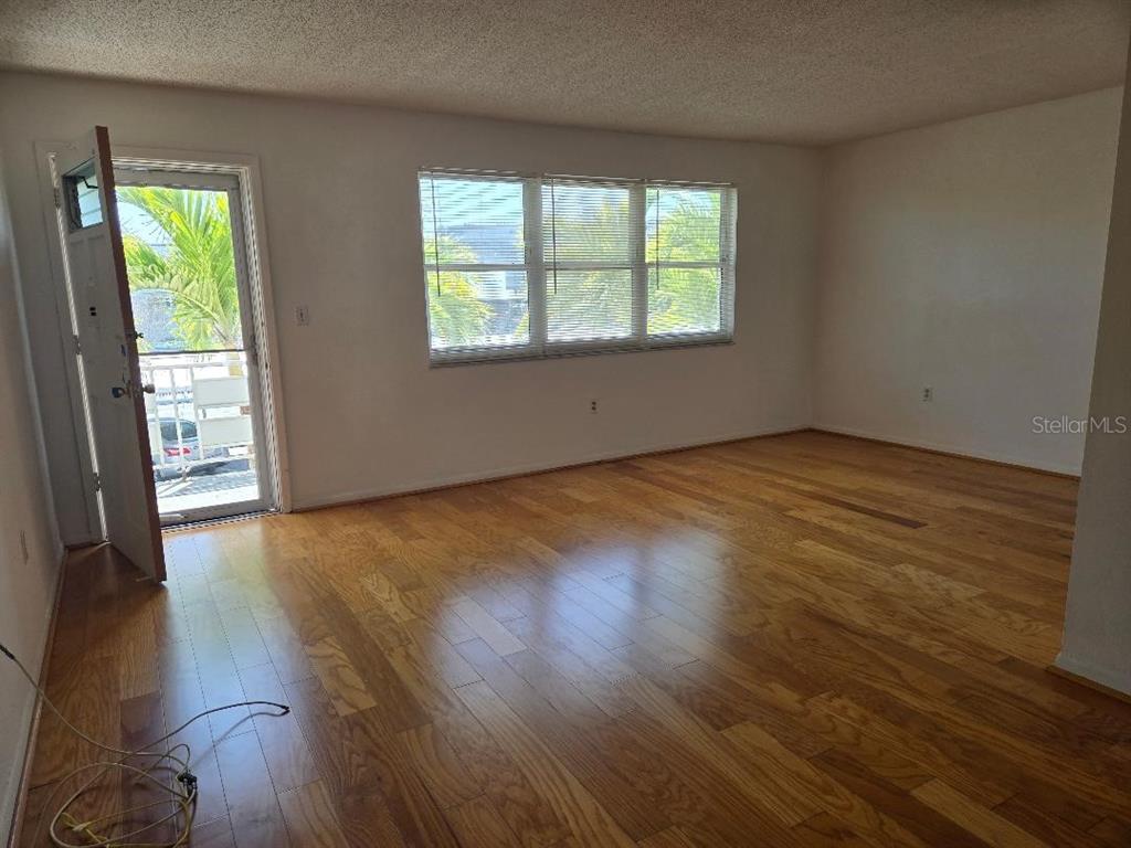An empty room with hardwood floors, a large window, and an open exterior door — 3128 59TH STREET S UNIT 205, GULFPORT, FL
