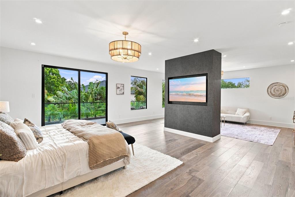 A spacious bedroom features a central dark accent wall with a television and balcony views — 1076 SNELL ISLE BOULEVARD NE, ST PETERSBURG, FL
