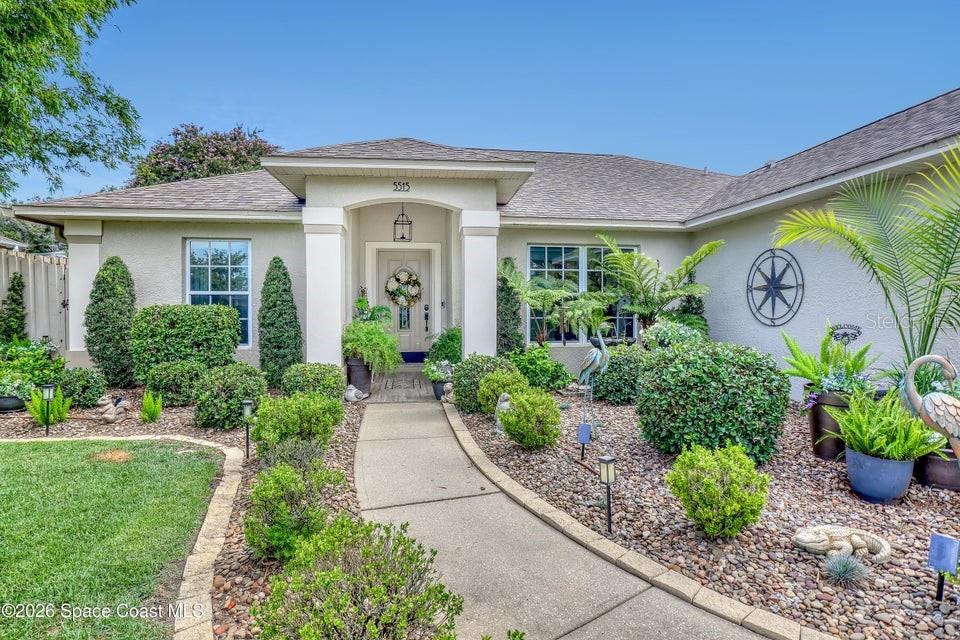 A single-story house exterior features a concrete walkway leading to a covered front entrance — 5515 OAK HOLLOW DRIVE, TITUSVILLE, FL