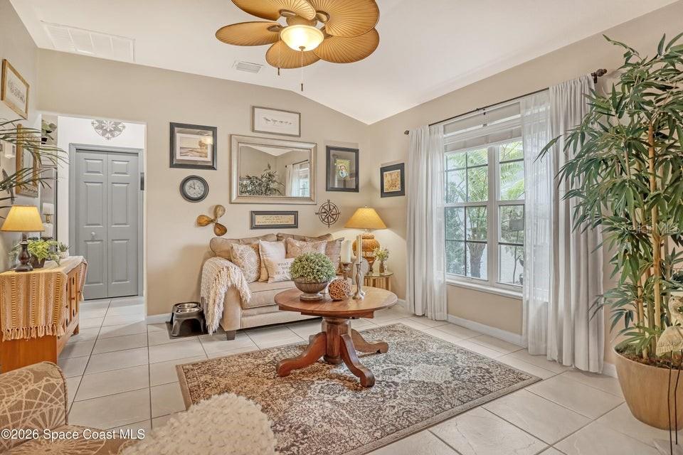 A living room features a beige sofa, a round wooden coffee table, and tile flooring — 5515 OAK HOLLOW DRIVE, TITUSVILLE, FL