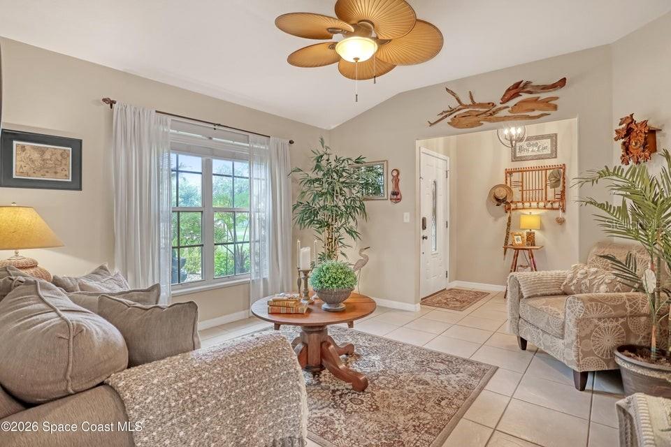 A living room features a ceiling fan, tile flooring, a round coffee table, and furniture — 5515 OAK HOLLOW DRIVE, TITUSVILLE, FL