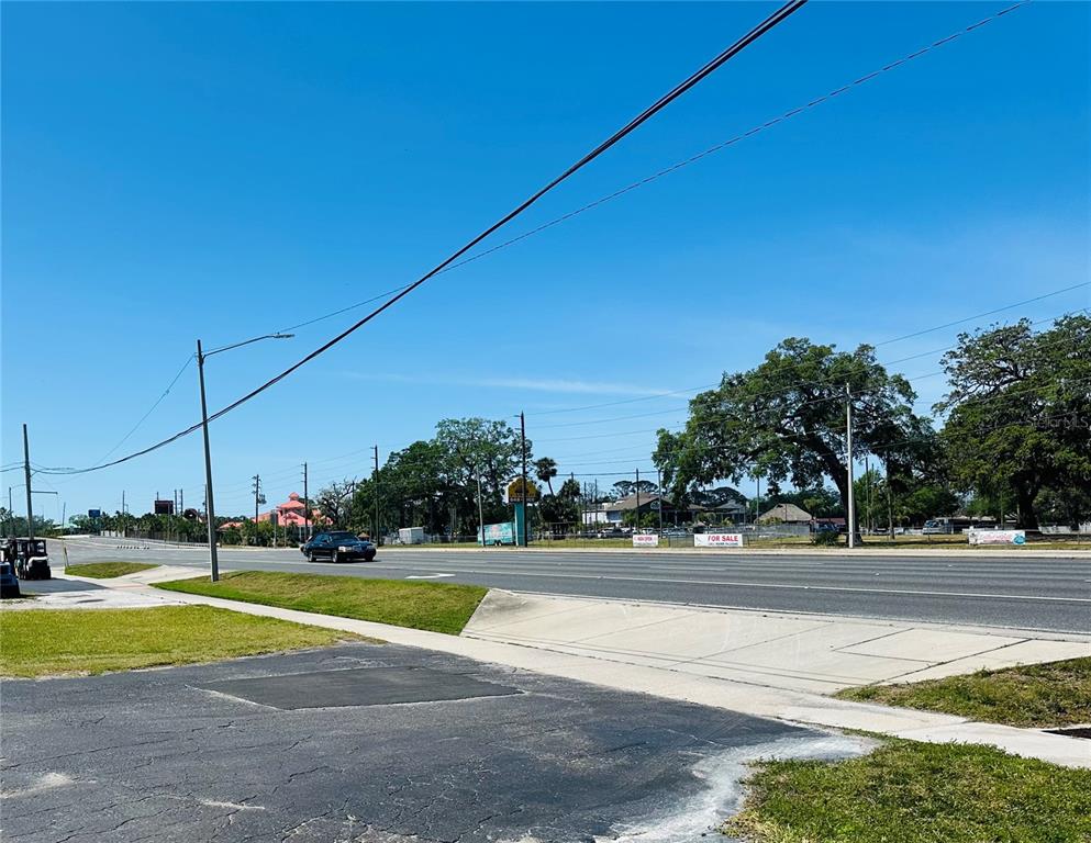 A view of a multi-lane road with a car driving past a grassy lot — 7904 US HIGHWAY 19, PORT RICHEY, FL