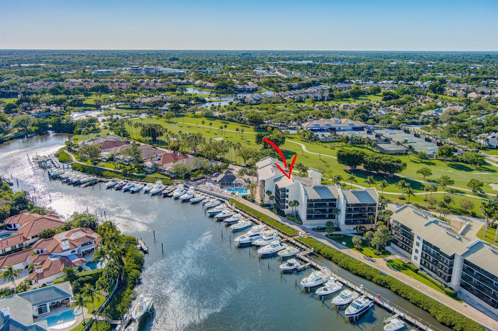An aerial view shows a multi-story waterfront condominium building with a private boat dock — 16910 Bay Street E # E503, Jupiter FL 33477, JUPITER, FL