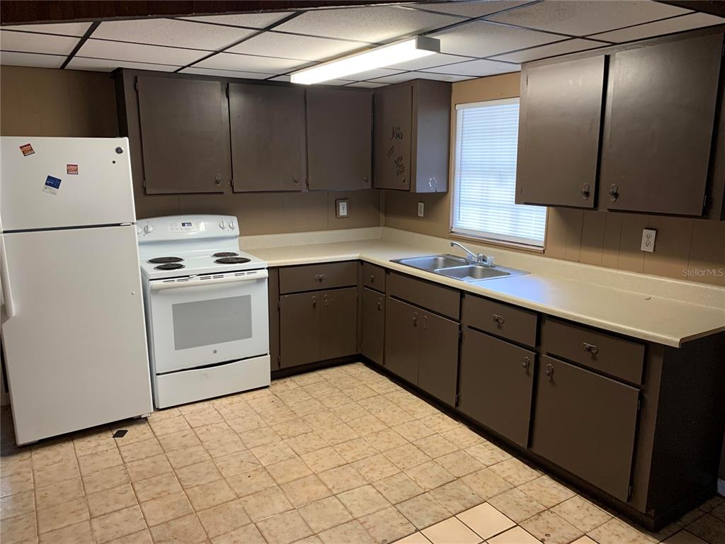 A kitchen features brown cabinets, white appliances, a double sink, and a tiled floor — 1838 NE 145TH AVENUE ROAD, SILVER SPRINGS, FL
