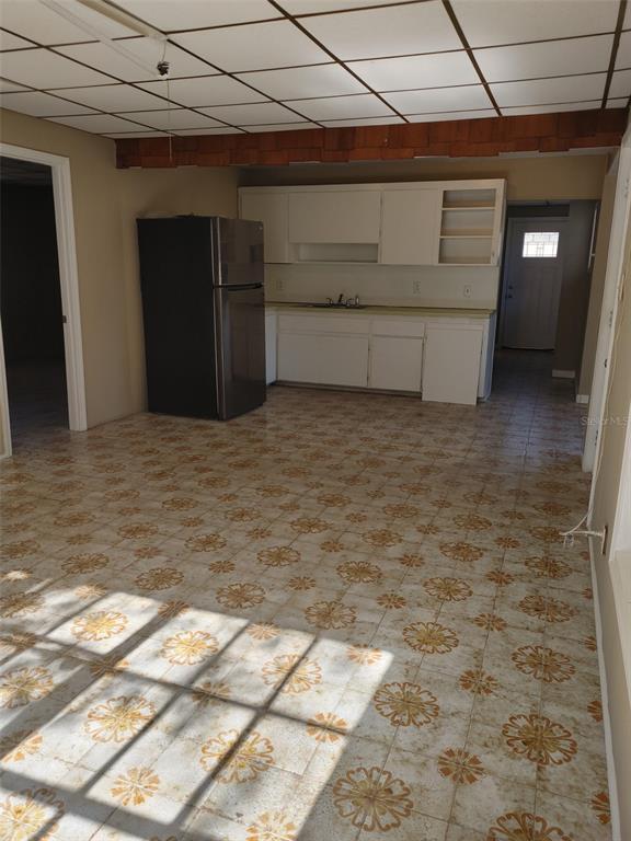 A kitchen features white cabinets, a dark refrigerator, and patterned tile flooring — 1838 NE 145TH AVENUE ROAD, SILVER SPRINGS, FL