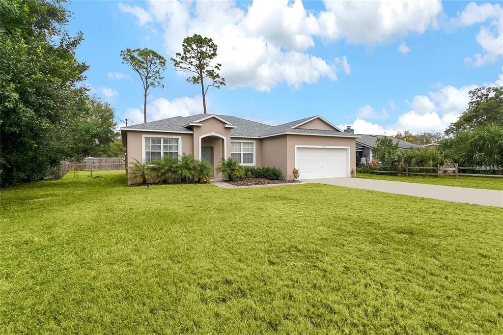 A single-story house with a tan exterior, a two-car garage, and a large front lawn — 2727 RAMSEY DRIVE, APOPKA, FL