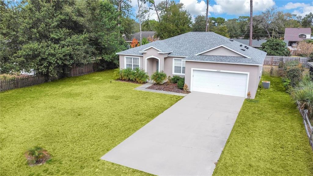An aerial view of a single-story house with a concrete driveway and a large lawn — 2727 RAMSEY DRIVE, APOPKA, FL