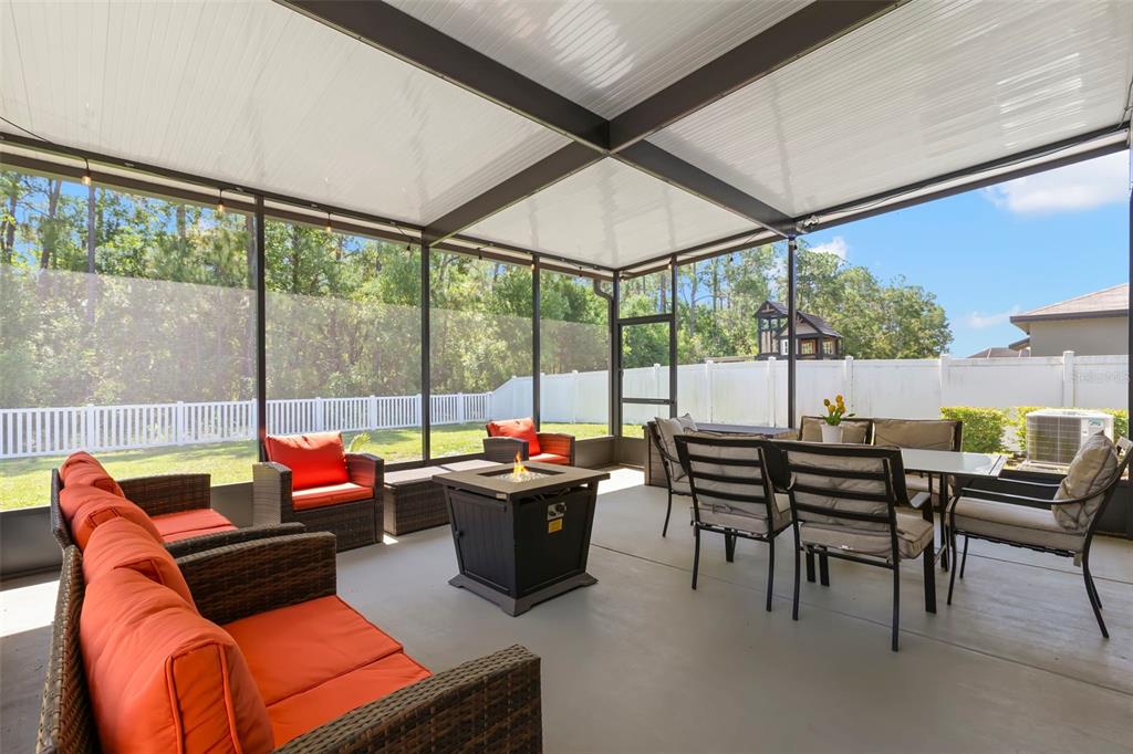 A screened-in patio with a fire pit, outdoor furniture, and a white vinyl fence — 13511 WILLOW BLUESTAR LOOP, RIVERVIEW, FL