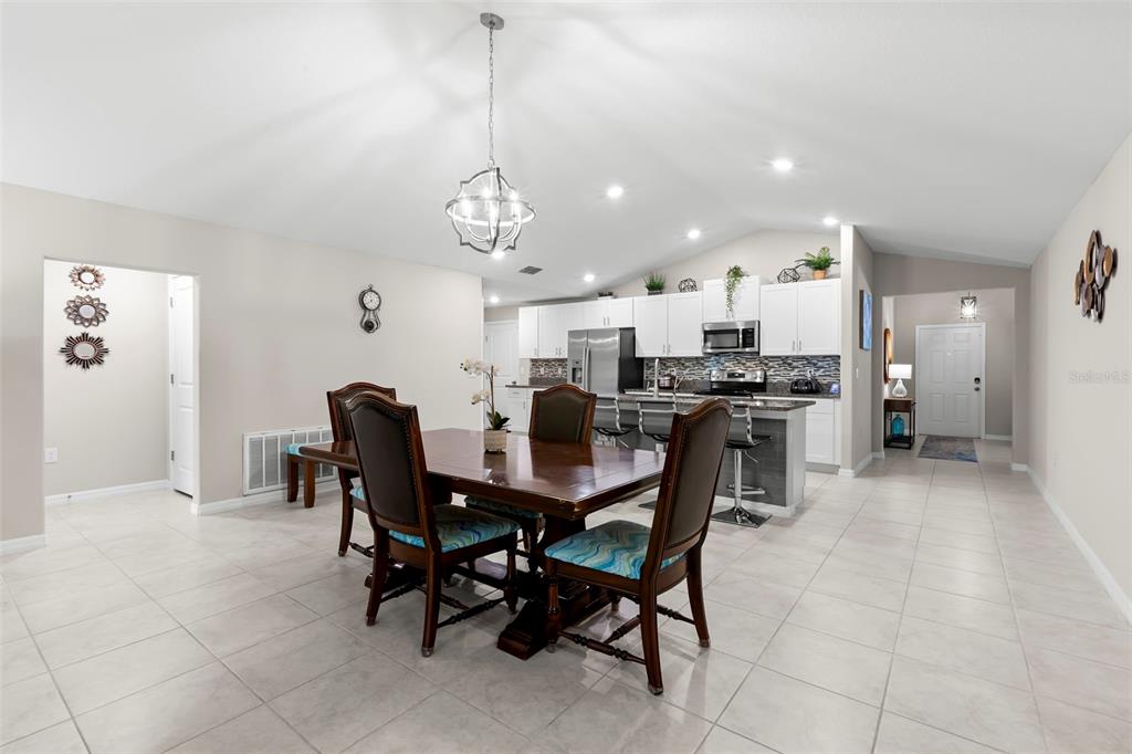 A dining area with a wooden table and chairs sits in front of an open kitchen — 13511 WILLOW BLUESTAR LOOP, RIVERVIEW, FL