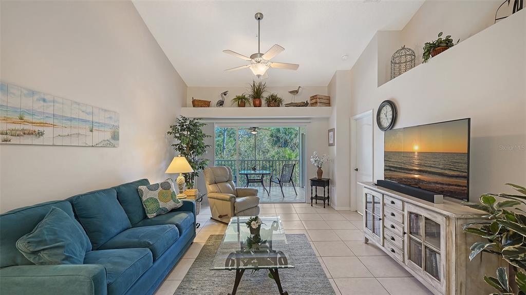 A living room features a blue sofa, a glass coffee table, and a balcony view — 4655 TOWER HILL LANE UNIT 2422, SARASOTA, FL