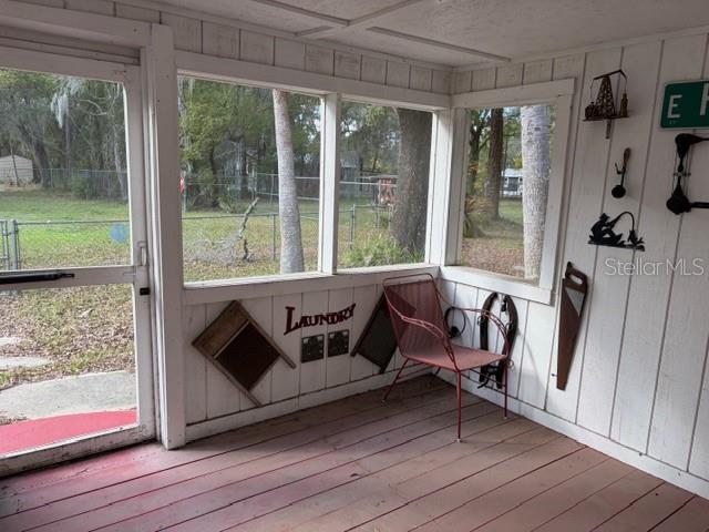 A screened-in porch features white wood-paneled walls, a red floor, and vintage decor — 6419 SE 215TH STREET, HAWTHORNE, FL