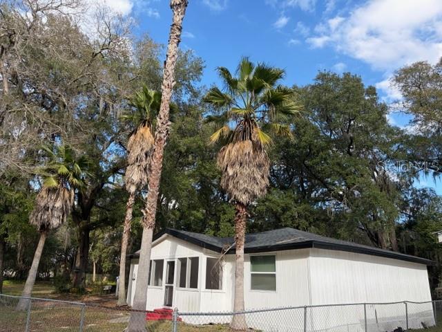 A white single-story house with a screened porch stands behind a chain-link fence — 6419 SE 215TH STREET, HAWTHORNE, FL
