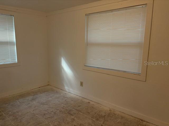 An empty room features white walls, two windows with closed blinds, and unfinished flooring — 6419 SE 215TH STREET, HAWTHORNE, FL