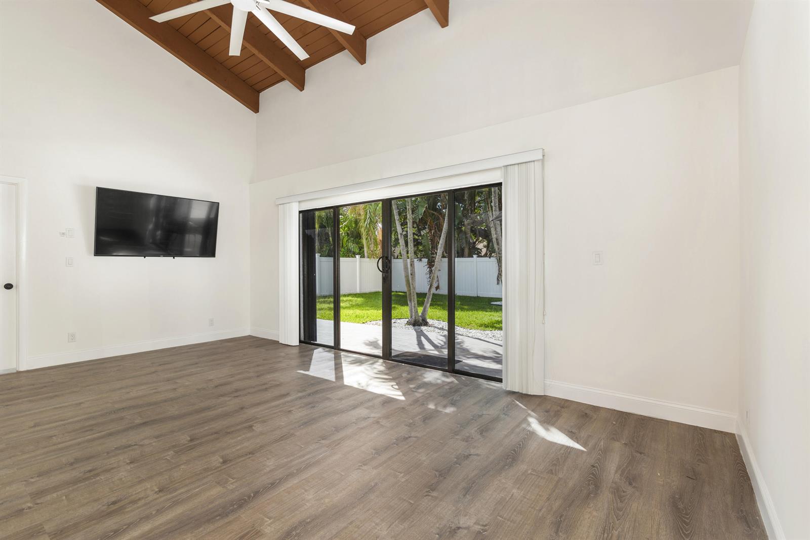 A living room features vaulted wood-paneled ceilings, wood-look flooring, and sliding glass doors to a yard — 2474 Douglas Avenue, Delray Beach FL 33444, DELRAY BEACH, FL