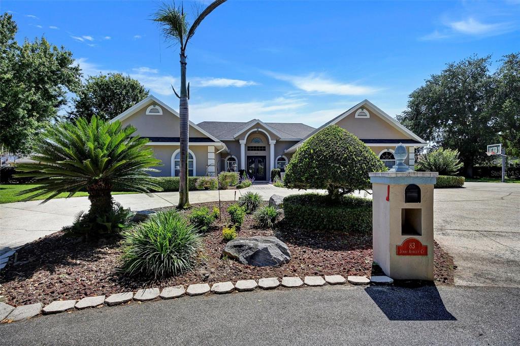 A paved walkway leads to a front entrance with double doors and two white columns — 83 JENNI ASHLEY COURT, WINTER HAVEN, FL