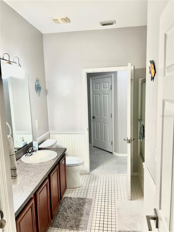 A bathroom features a vanity with a dark countertop, a toilet, and tiled flooring — 17274 ASMARA COURT, PUNTA GORDA, FL