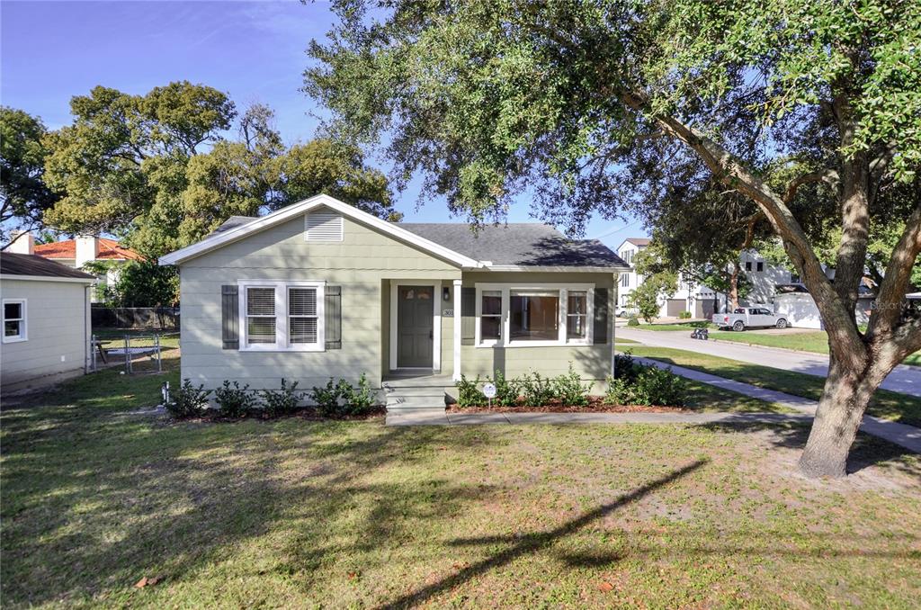 A single-story house with light green siding and a dark front door sits on a lawn — 301 S AUDUBON AVENUE, TAMPA, FL