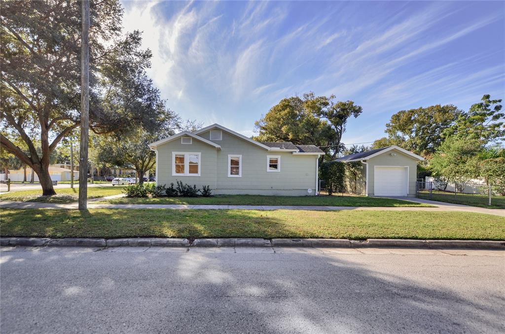 A light green single-story house with a detached garage sits behind a grassy lawn — 301 S AUDUBON AVENUE, TAMPA, FL