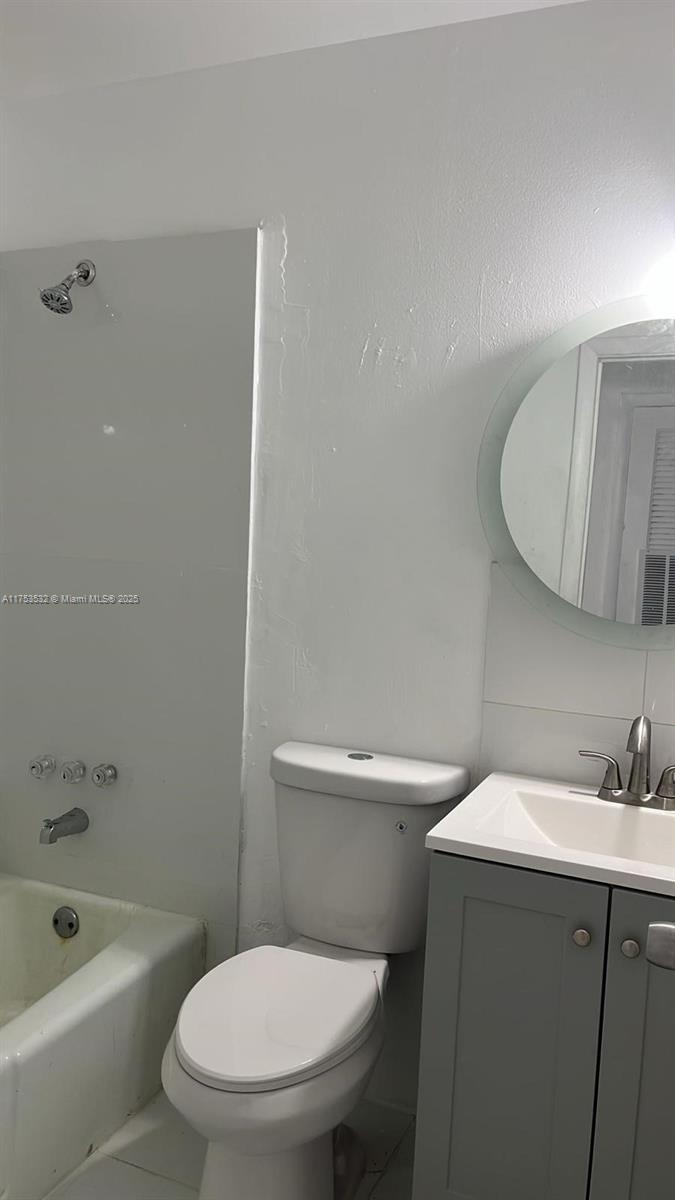 A bathroom features a white toilet, a gray vanity with a sink, and a bathtub — 550 NE 44th St # M2, Deerfield Beach FL 33064, DEERFIELD BEACH, FL