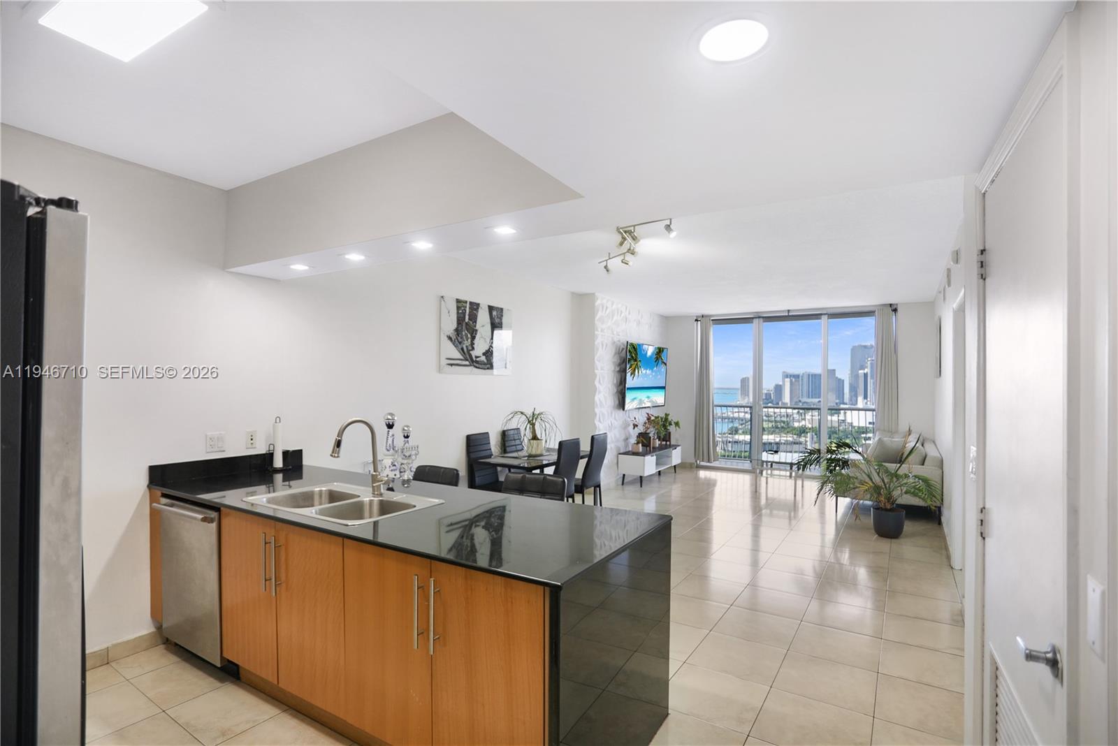 A kitchen with wood cabinets and black countertops opens into a living area with city views — 1750 N Bayshore Dr # 3210, Miami FL 33132, MIAMI, FL