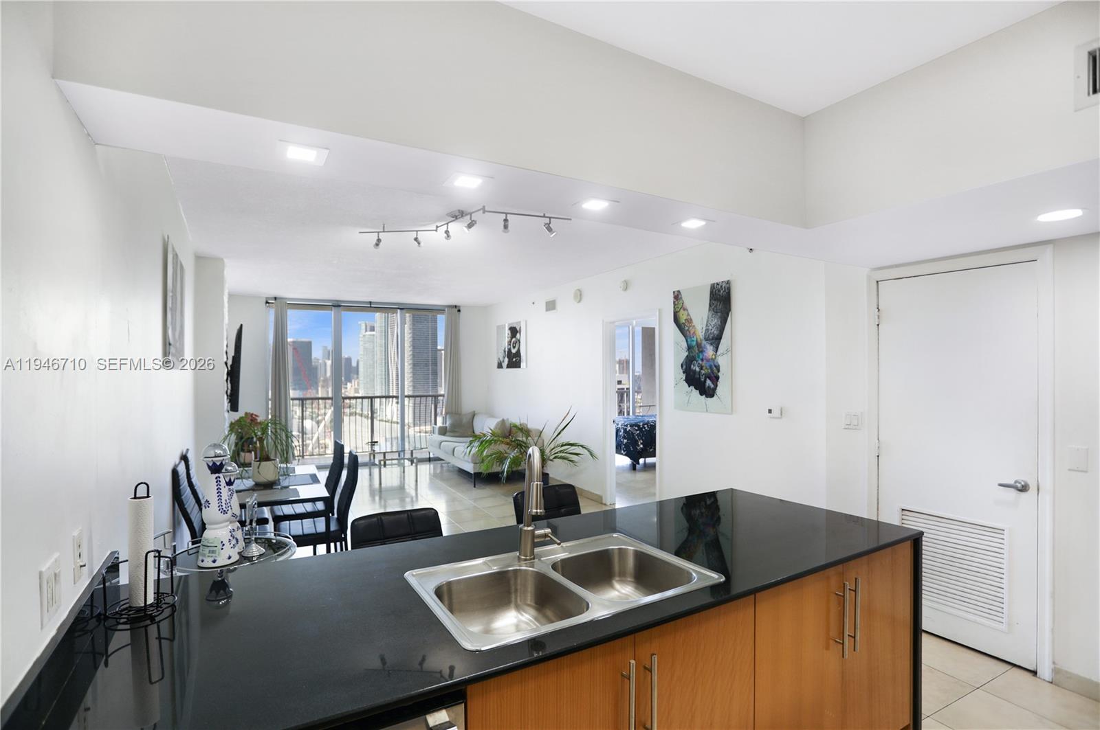 A kitchen island with a double sink overlooks a living area with floor-to-ceiling windows — 1750 N Bayshore Dr # 3210, Miami FL 33132, MIAMI, FL