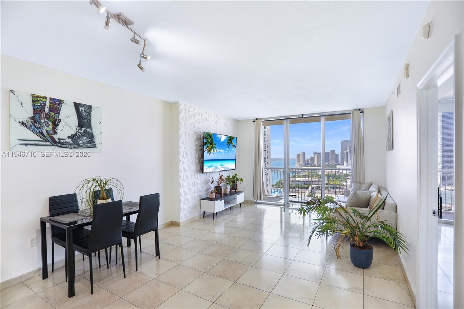 A bright living and dining area features tile floors, a textured accent wall, and balcony views — 1750 N Bayshore Dr # 3210, Miami FL 33132, MIAMI, FL