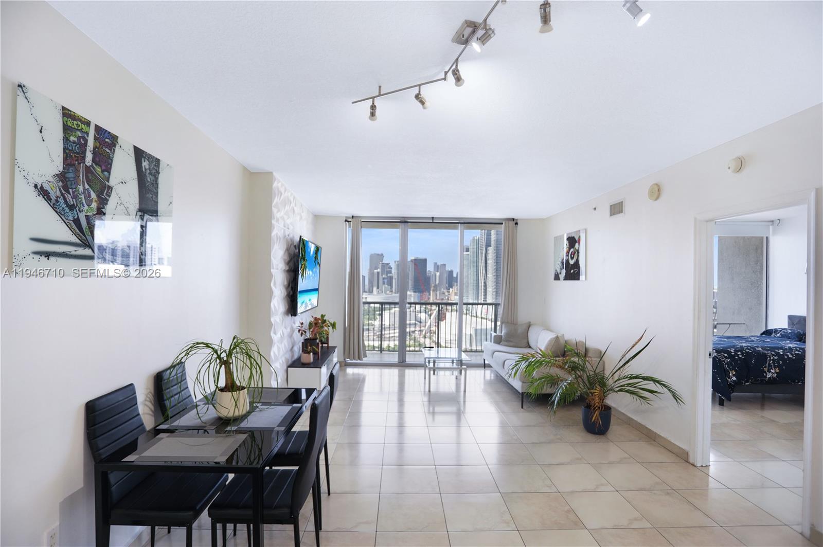 A living and dining area features tile floors, a city view, and a bedroom entrance — 1750 N Bayshore Dr # 3210, Miami FL 33132, MIAMI, FL