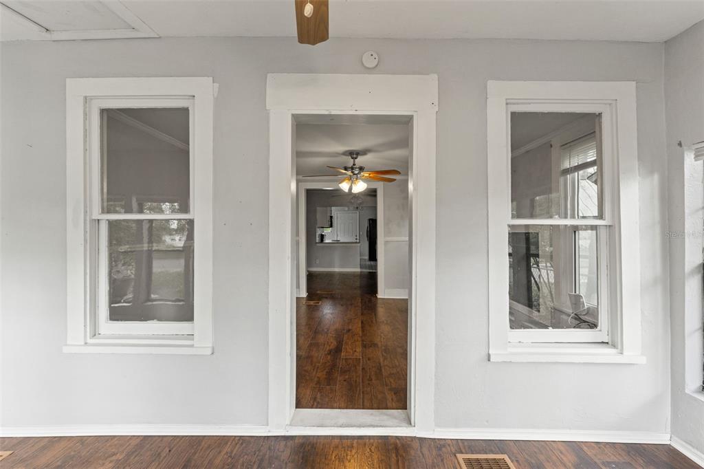 A view through a doorway into a living area with wood-look flooring and ceiling fans — 5518 11TH STREET, ZEPHYRHILLS, FL