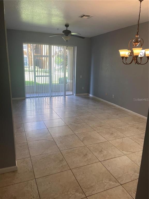 An open dining area features light-colored tile flooring, gray walls, and a hanging chandelier — 6451 OLD PARK LN UNIT 102, ORLANDO, FL