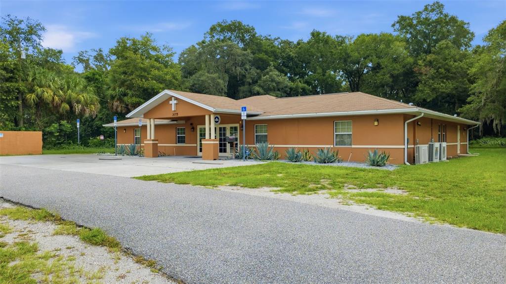 A single-story tan building with a cross on the gable and a paved parking area — 3075 N GOLDENROD ROAD, WINTER PARK, FL