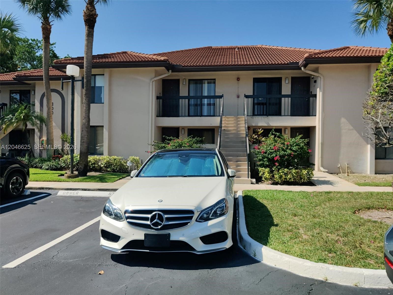 A white Mercedes-Benz is parked in front of a two-story apartment building with balconies — 300 E Club Cir # 108, Boca Raton FL 33487, BOCA RATON, FL