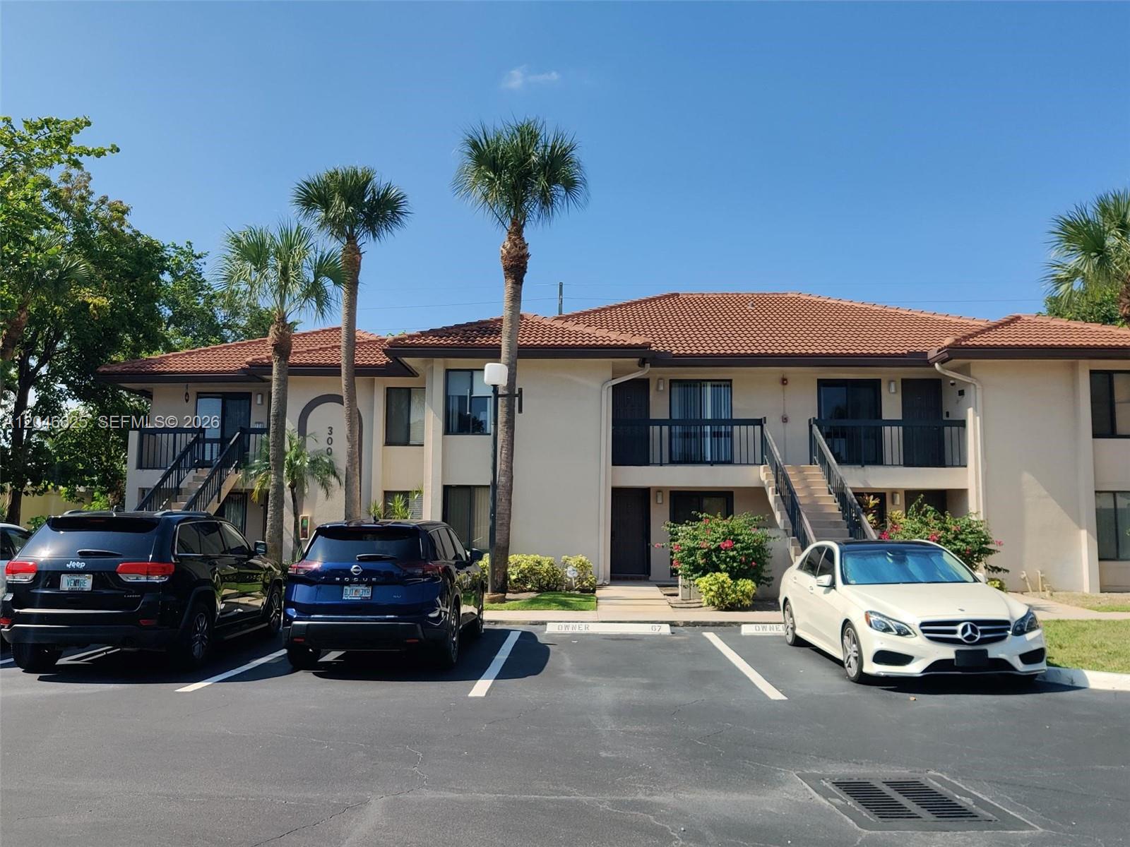 A two-story apartment building with a tiled roof and parking spaces in front — 300 E Club Cir # 108, Boca Raton FL 33487, BOCA RATON, FL