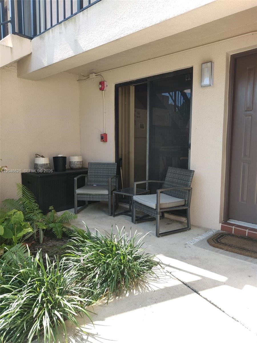 A ground-level patio features two wicker chairs, a small table, and a storage bin — 300 E Club Cir # 108, Boca Raton FL 33487, BOCA RATON, FL