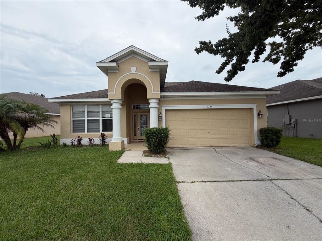 A single-story house with a beige stucco exterior, a two-car garage, and a covered entryway — 2445 CYPRESS TRACE CIRCLE, ORLANDO, FL