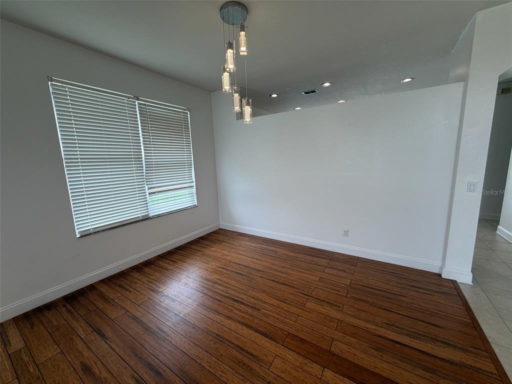 An empty dining room features dark wood flooring, white walls, and a modern pendant light — 2445 CYPRESS TRACE CIRCLE, ORLANDO, FL